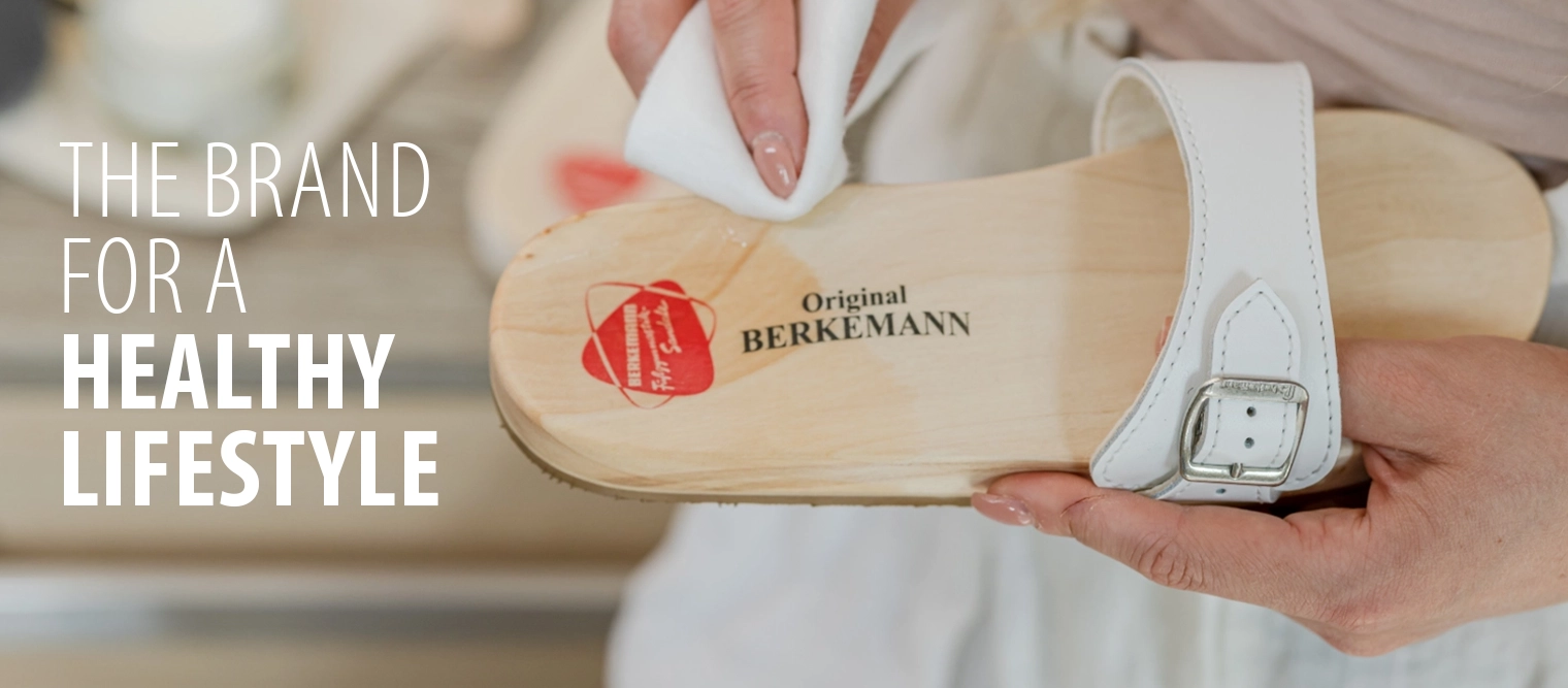 Frau pflegt eine weiße Berkemann Original Sandale mit einem Tuch und Pflegemittel.