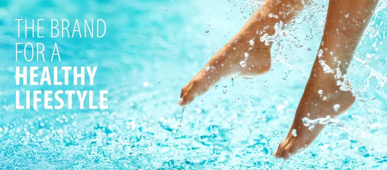 Barfuße Füße einer Person, die über Wasser hängen und Spritzer verursachen.